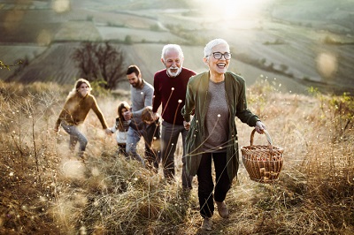 Happy senior woman leading her family to perfect picnic place on the hill.